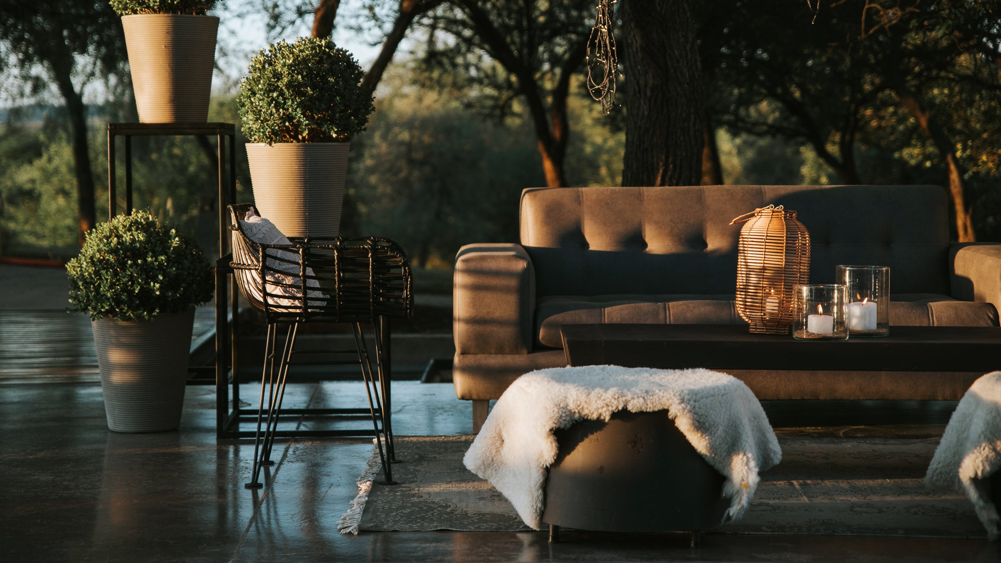 Outdoor patio with modern furniture, including a sofa, coffee table, and planters, arranged in a serene garden setting.