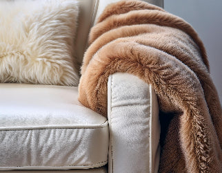 Luxurious white leather sofa with a soft, brown faux fur throw and a fluffy cushion, creating a cozy and elegant living room ambiance.