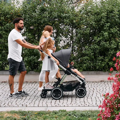 Family using ABC Design Kiddie Ride On 2 Board with stroller, showcasing luxury and modern furniture concepts in outdoor setting.