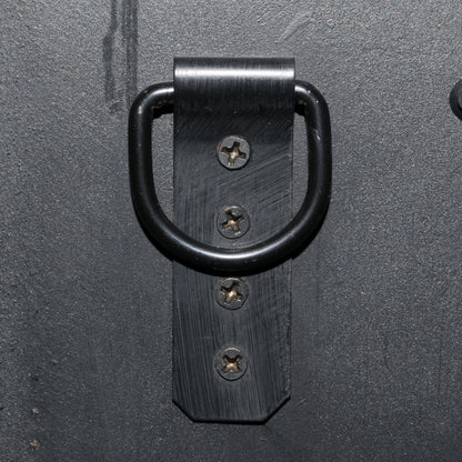 Close-up of a sturdy black metal hanging bracket with screws on a wall, ideal for secure installation of mirrors or frames.