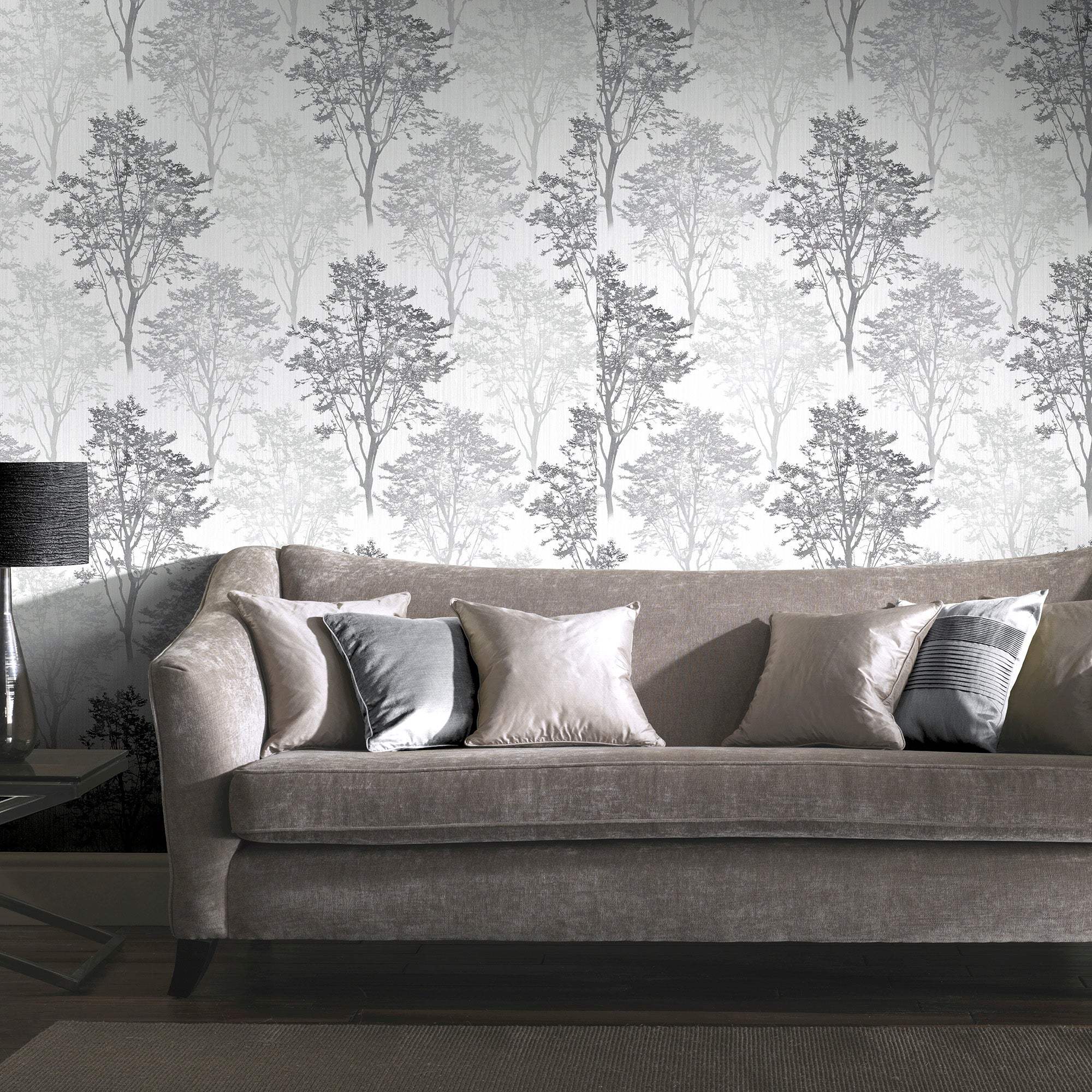 Elegant living room with tree-patterned wallpaper and plush gray sofa adorned with stylish cushions, featuring modern home decor.
