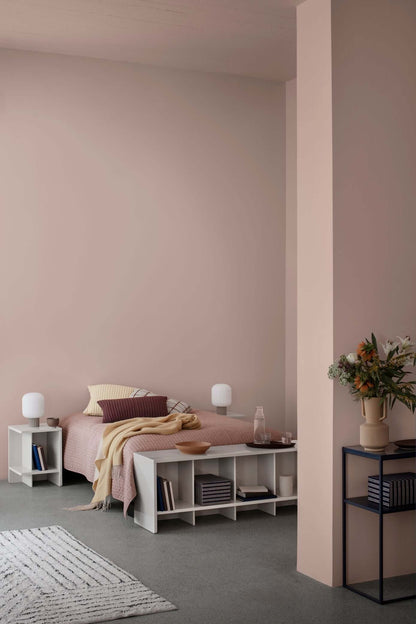 Modern bedroom with minimalist decor, featuring a bed, bedside tables with lamps, and a cushy rug on smooth flooring.
