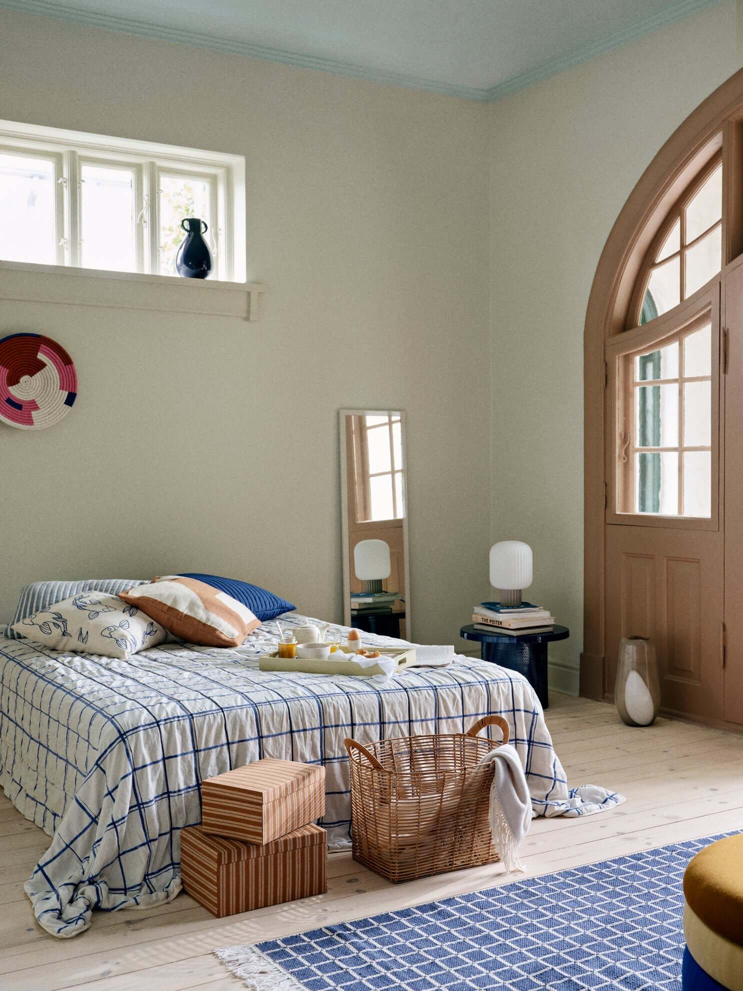 Cozy bedroom featuring modern decor with elegant linens, a basket, and a Lolly Table Lamp enhancing the tranquil ambiance.