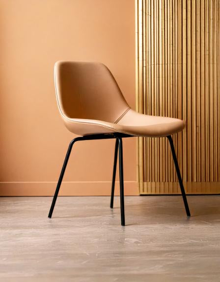Modern tan chair with black legs against a textured tan background, featuring sleek minimalist design.