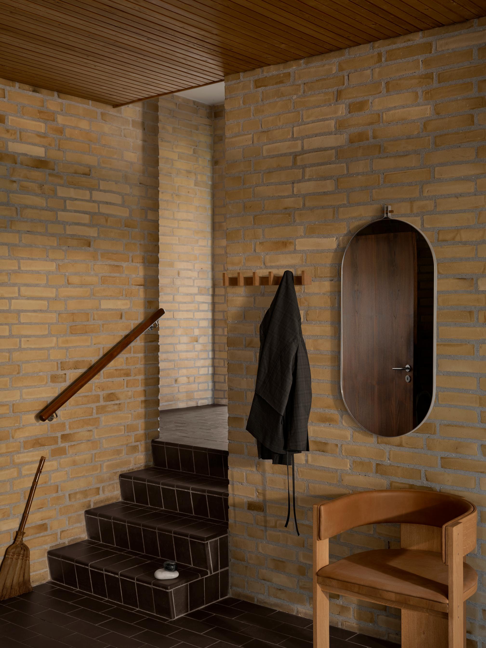 Collector Dining Chair in leather against a brick wall, showcasing luxury and designer furniture aesthetics for premium home decor.