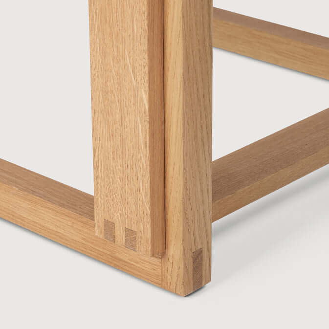Close-up of Outline Chair's FSC-certified oak legs, highlighting minimalist design in luxury furniture for modern interiors.
